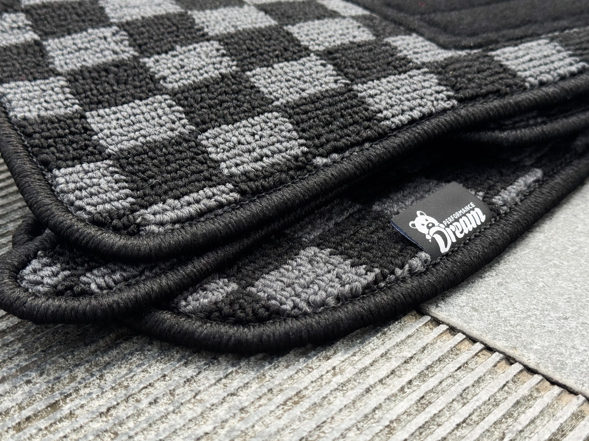 Nissan Skyline GTR R34 BNR34 GTT checker floor mats stacked corner detail with Dream Performance label