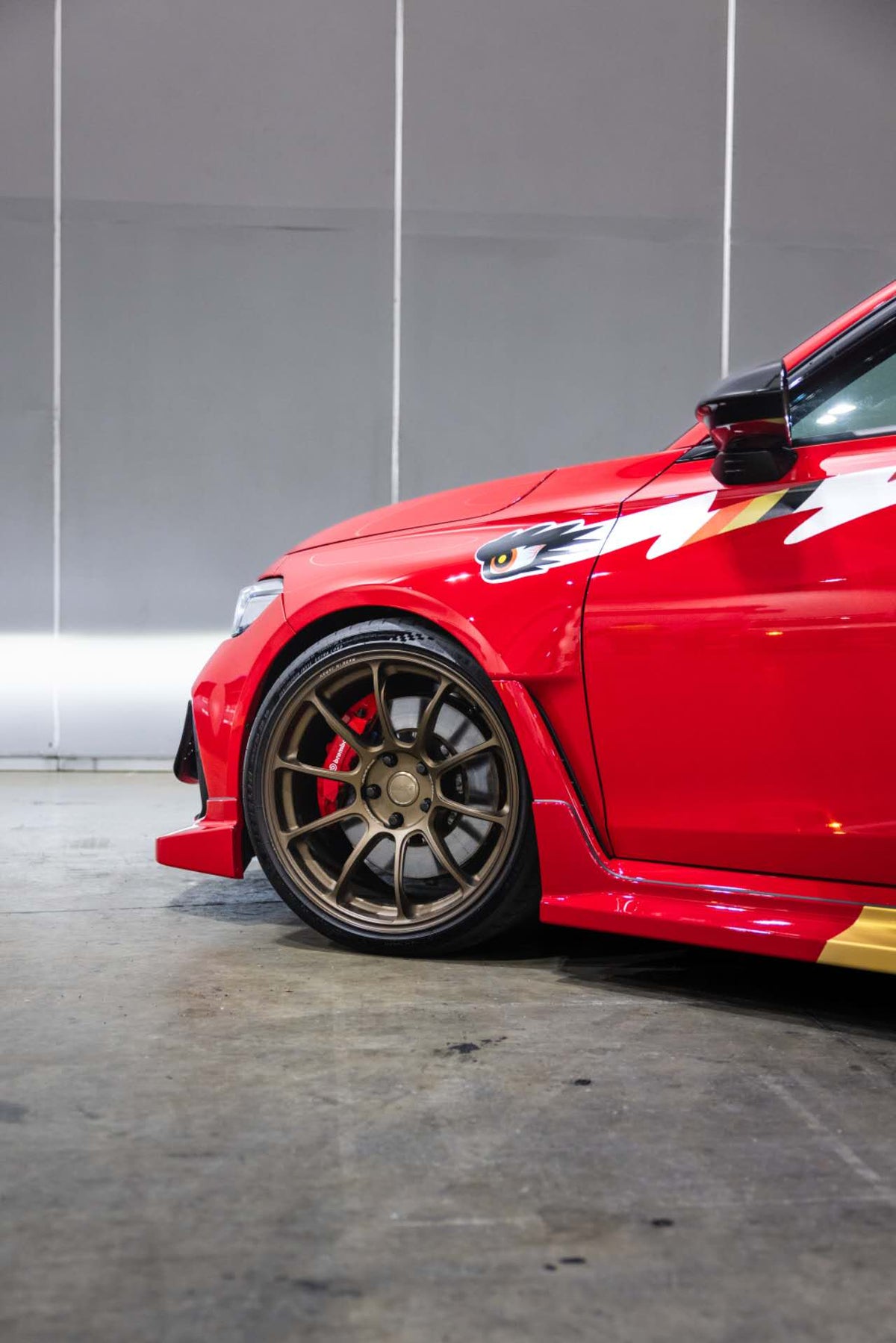 Front guard detail of a red FL5 Civic Type R showing where the winged eye graphic sits above the wheel arch