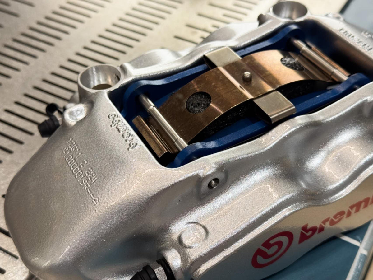 Brembo F50 caliper showing brake pads, retaining pins and anti rattle spring