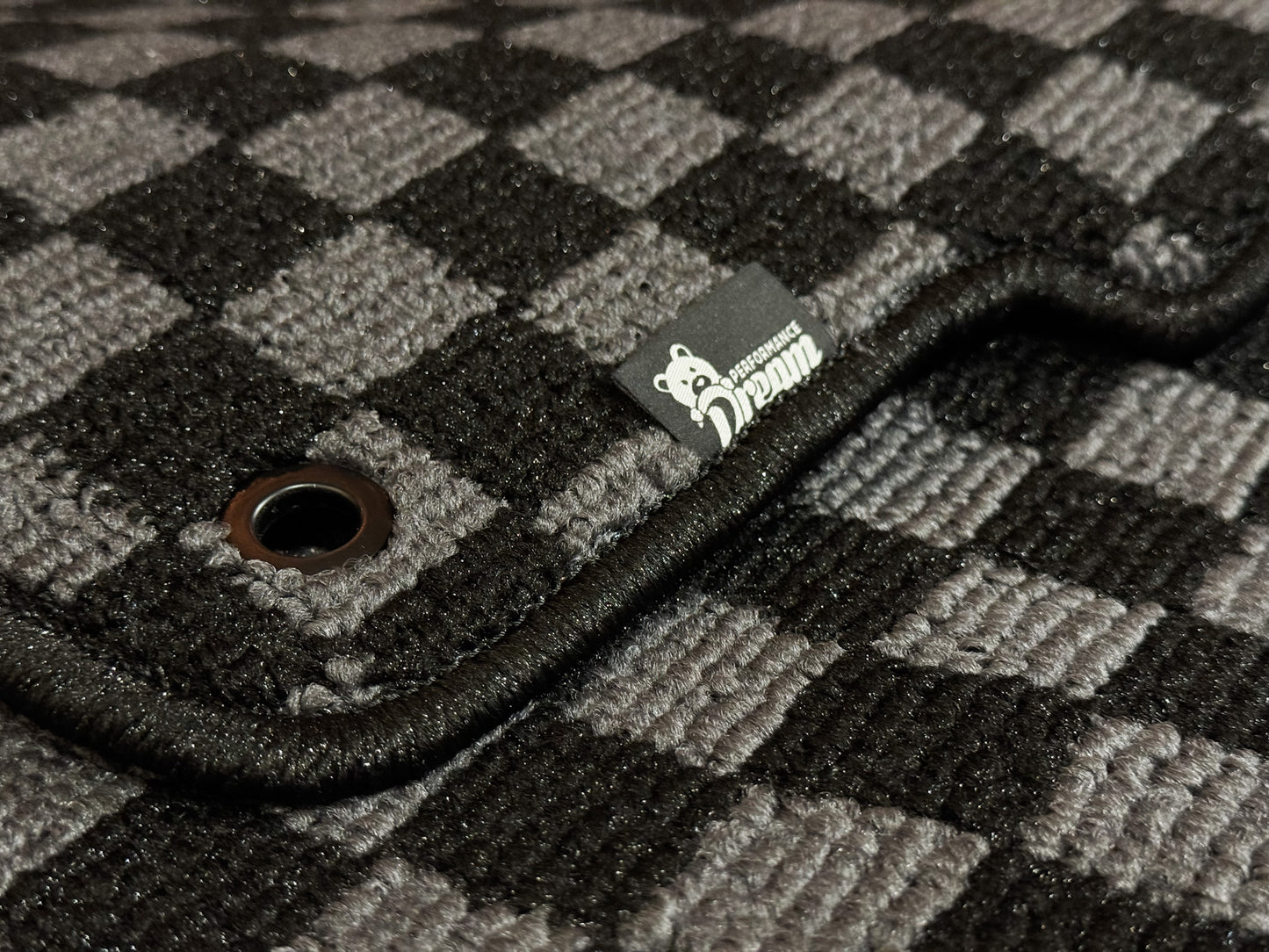 Close up of checker carpet weave, metal fixing eyelet and Dream Performance badge