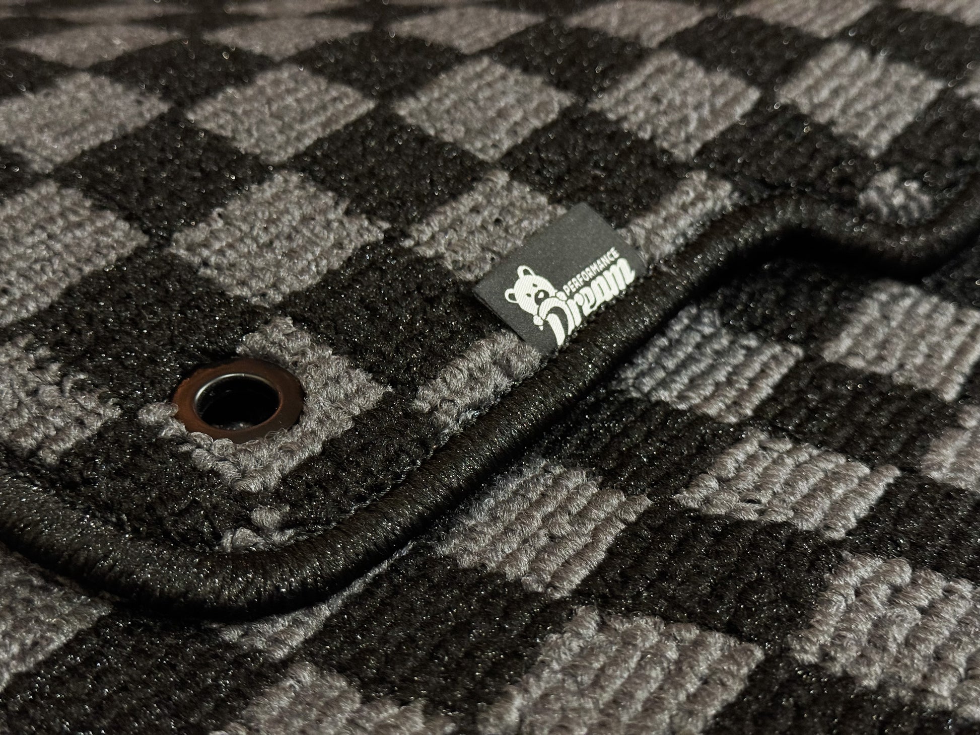 Close up of checker carpet weave, metal fixing eyelet and Dream Performance badge