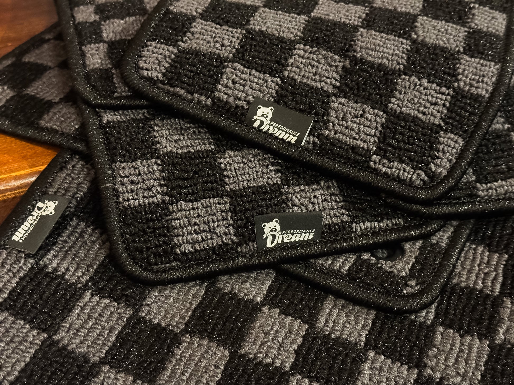Stacked checker floor mats showing the bound edges and branded tags