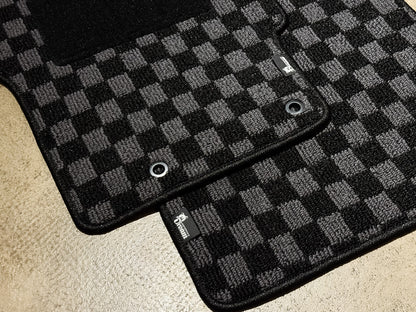 Two checker floor mats overlapping, showing the chrome fixing eyelets